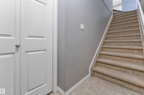 Carpeted staircase with white trim, gray wall, and panel doors - #102 3040 Spence Wd Sw, Edmonton, AB - Indoor Photo Showing Other Room