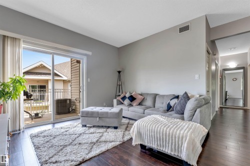 Living area featuring dark wood-finish flooring and light gray walls - #102 3040 Spence Wd Sw, Edmonton, AB - Indoor Photo Showing Living Room