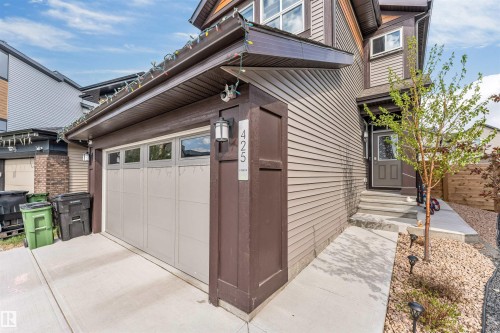 Contemporary facade featuring tan horizontal siding, a light-colored garage door with window inserts, and dark trim details - 425 41 Street, Edmonton, AB - Outdoor