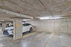 Dedicated parking space within a concrete parking structure, featuring painted yellow parking lines, exposed concrete walls, and overhead lighting fixtures - 
