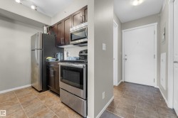 Compact kitchen featuring dark wood cabinetry, stainless steel appliances, and a tile backsplash - 