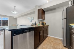 Open-concept kitchen featuring dark wood cabinetry, stainless steel appliances, and a peninsula with countertop seating - 