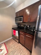 Full kitchen featuring dark wood cabinetry, stainless steel appliances, dark countertops, and wood-finish flooring - 
