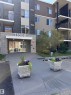 Multi-level building exterior featuring a stone-look entrance, glass double doors, and private balconies - #419 11808 22 Av Sw, Edmonton, AB  - Outdoor With Balcony 