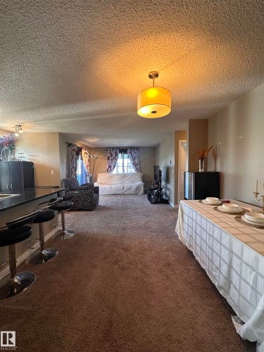 Open-concept living space featuring textured ceilings, recessed lighting, and a drum pendant light fixture - #419 11808 22 Av Sw, Edmonton, AB - Indoor