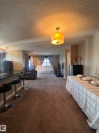 Open-concept living space featuring textured ceilings, recessed lighting, and a drum pendant light fixture - 