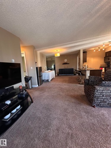 Expansive open-concept living area featuring a neutral carpet flooring - #419 11808 22 Av Sw, Edmonton, AB - Indoor Photo Showing Living Room