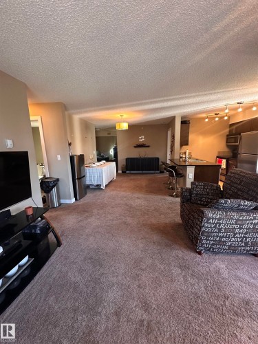 Expansive interior with textured ceilings and brown carpeting throughout - #419 11808 22 Av Sw, Edmonton, AB - 