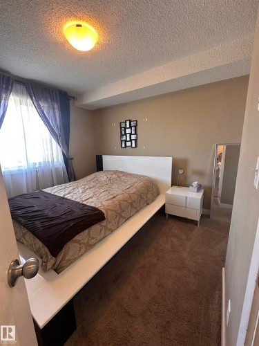 Textured ceiling with a flush-mount overhead light fixture - #419 11808 22 Av Sw, Edmonton, AB - Indoor Photo Showing Bedroom
