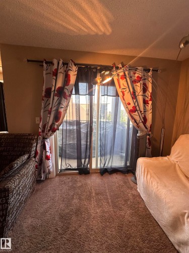 Sliding glass door opening to an outdoor area, featuring neutral-toned carpeting and light-colored walls - #419 11808 22 Av Sw, Edmonton, AB - Indoor