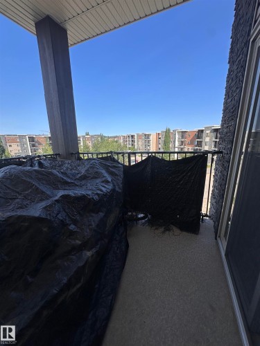 Private balcony featuring a concrete floor, black metal railing, and an adjacent exterior wall with dark stone-look siding - #419 11808 22 Av Sw, Edmonton, AB - Outdoor