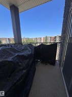 Private balcony featuring a concrete floor, black metal railing, and an adjacent exterior wall with dark stone-look siding - 