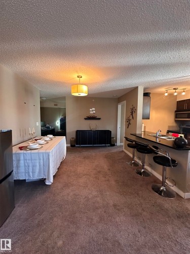Open-concept living space featuring textured ceilings, neutral wall tones, and recessed lighting - #419 11808 22 Av Sw, Edmonton, AB - Indoor