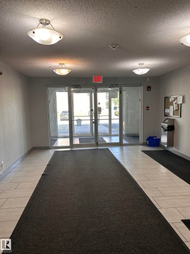 Entryway featuring glass double doors, white tile flooring, and multiple ceiling-mounted light fixtures - #419 11808 22 Av Sw, Edmonton, AB - Indoor Photo Showing Other Room