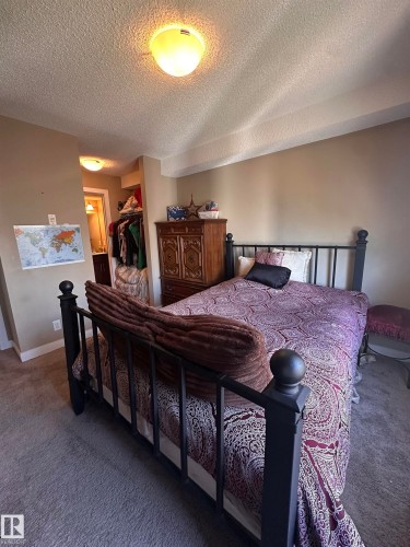 Carpeted bedroom with neutral wall tones and a built-in closet visible through an open doorway - #419 11808 22 Av Sw, Edmonton, AB - Indoor Photo Showing Bedroom