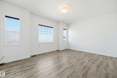 Spacious room featuring light wood-finish flooring, white baseboards, and multiple windows with grids - 1 Southfork Close, Leduc, AB - Indoor Photo Showing Other Room