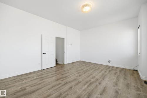 Spacious room featuring wood-finish flooring, white baseboards, and a flush-mount ceiling light fixture - 1 Southfork Close, Leduc, AB - Indoor Photo Showing Other Room