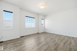 Spacious room featuring light wood-finish flooring, white baseboards, and multiple windows with grids - 