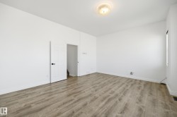 Spacious room featuring wood-finish flooring, white baseboards, and a flush-mount ceiling light fixture - 
