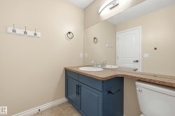 Bathroom featuring a dual vanity with a dark blue cabinet, light speckled countertop, and two integrated sinks - 