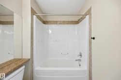 Tub and shower combination featuring an integrated white surround and polished chrome fixtures - 