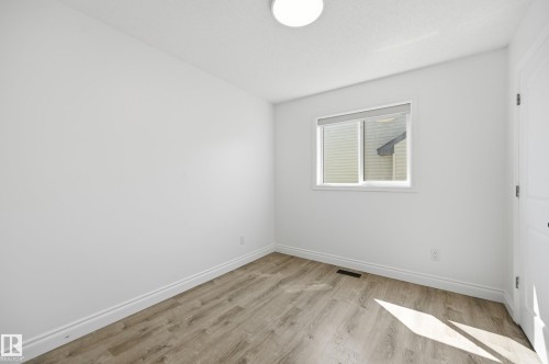 Bright room with a single window, overhead flush-mount lighting, wood-finish flooring, white baseboards, and a paneled door - 1 Southfork Close, Leduc, AB - Indoor Photo Showing Other Room