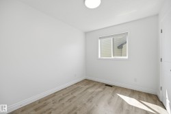 Bright room with a single window, overhead flush-mount lighting, wood-finish flooring, white baseboards, and a paneled door - 