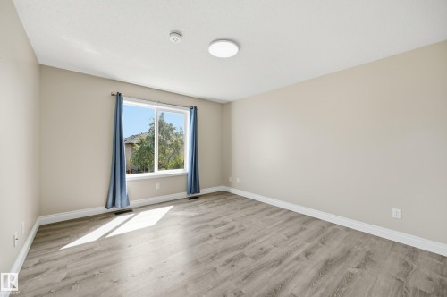 Spacious room with wood-finish flooring, neutral-toned walls, a large window, and white trim - 1 Southfork Close, Leduc, AB - Indoor Photo Showing Other Room