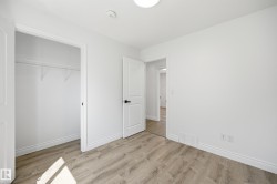 Bright interior room featuring wood-finish flooring, white walls, and a white ceiling with a flush-mount light fixture - 