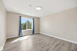 Spacious room with wood-finish flooring, neutral-toned walls, a large window, and white trim - 
