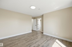 Spacious room featuring wood-finish flooring, light neutral wall paint, white trim, and a contemporary flush-mount ceiling light - 