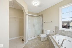 Spacious bathroom featuring a built-in soaking tub with chrome fixtures, a separate glass-enclosed shower, a large window, and tile flooring - 