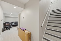 Staircase with light wood-finish treads and dark anti-slip strips, featuring a white handrail - 