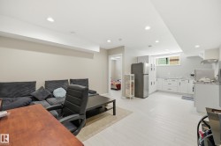 Open-concept living space featuring recessed lighting, light-toned flooring, and a modern kitchen area - 