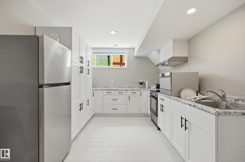 Contemporary kitchen featuring white cabinetry with matte black hardware, stainless steel appliances, and light-toned wood-finish flooring - 1 Southfork Close, Leduc, AB - Indoor Photo Showing Kitchen With Double Sink