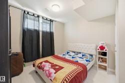 Bedroom featuring light-toned walls, white wood-finish flooring, and a white upholstered headboard - 