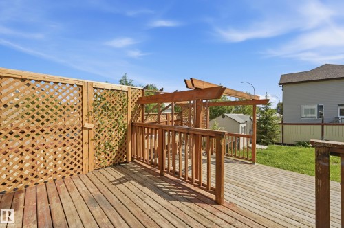 Expansive wood deck with a built-in pergola structure, featuring durable wood-plank flooring and natural wood lattice privacy fencing - 1 Southfork Close, Leduc, AB - Outdoor With Deck Patio Veranda