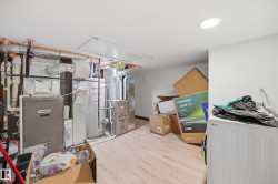 Utility area featuring a Lennox furnace, water heater, and wood-finish flooring - 