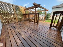 Wood-finish deck with lattice privacy screen, wood pergola, and railing - 