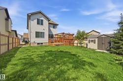 Spacious backyard featuring a large green lawn, multi-level wood deck, and a detached storage shed - 