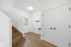 Entryway featuring a decorative glass front door, wood-finish flooring, a built-in floating bench, and a staircase with wood treads - 