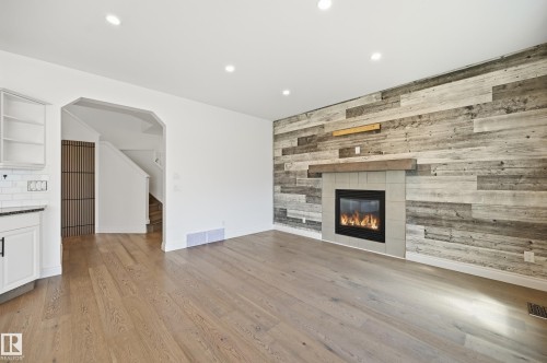 Living area featuring a reclaimed wood-style accent wall with a built-in fireplace and wood mantel - 1 Southfork Close, Leduc, AB - Indoor Photo Showing Living Room With Fireplace