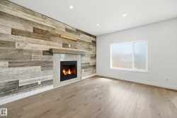 Living space featuring a tiled fireplace with a concrete mantel, wood-finish accent wall, recessed lighting, and a large window - 