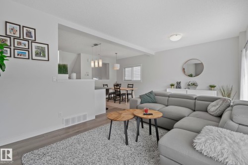 Open-concept living area featuring light gray walls, wood-finish flooring, and a dining space with modern pendant lighting - 249 39A Avenue, Edmonton, AB - Indoor Photo Showing Living Room