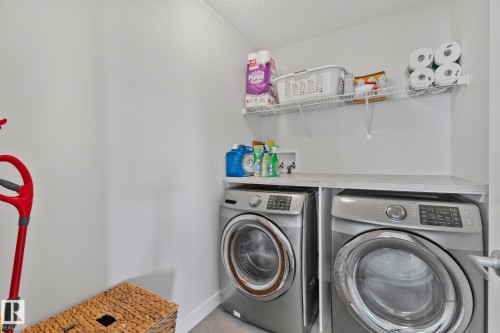 Dedicated laundry area featuring a built-in countertop, upper wire shelving, and space for side-by-side appliances - 249 39A Avenue, Edmonton, AB - Indoor Photo Showing Laundry Room
