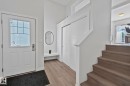 Bright entryway featuring a white paneled door with glass inserts, wood-finish flooring, a built-in white bench, and a white staircase with wood-finish treads - 249 39A Avenue, Edmonton, AB  - Indoor Photo Showing Other Room 