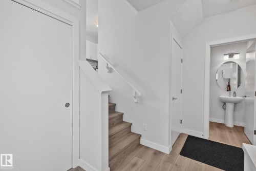 Entryway featuring wood-finish flooring, white walls, and a modern staircase with a white railing - 249 39A Avenue, Edmonton, AB - Indoor Photo Showing Other Room