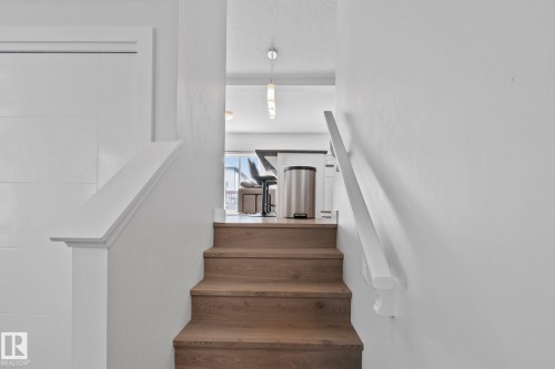 Wood-finish stair treads with white risers and handrails, leading to an upper level - 249 39A Avenue, Edmonton, AB - Indoor Photo Showing Other Room