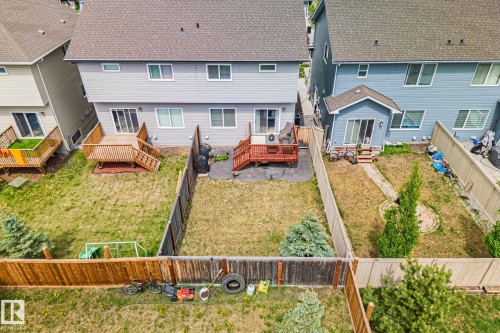 Expansive fenced backyard with a wood deck, sliding glass door access, and mature evergreen landscaping - 249 39A Avenue, Edmonton, AB - Outdoor