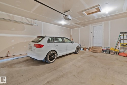 Spacious garage featuring a concrete floor, light-colored drywall walls, a white paneled door, and exposed ceiling joists - 249 39A Avenue, Edmonton, AB - Indoor Photo Showing Garage